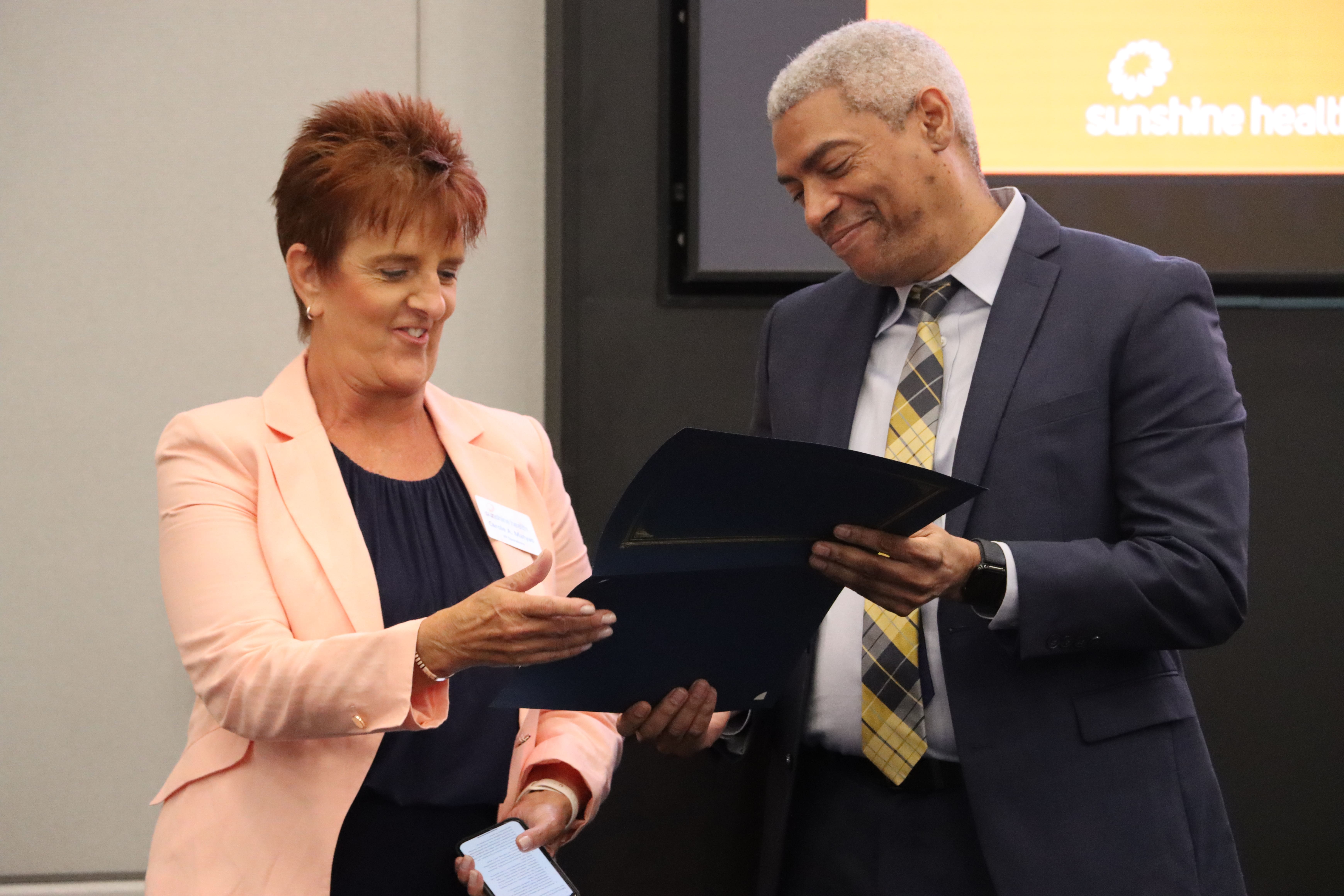 Chris Simmons presents Carole Maytas, vice president of operations for Sunshine Health, with an award at at the school's Social Work Month Celebration hosted at Centene's headquarters.